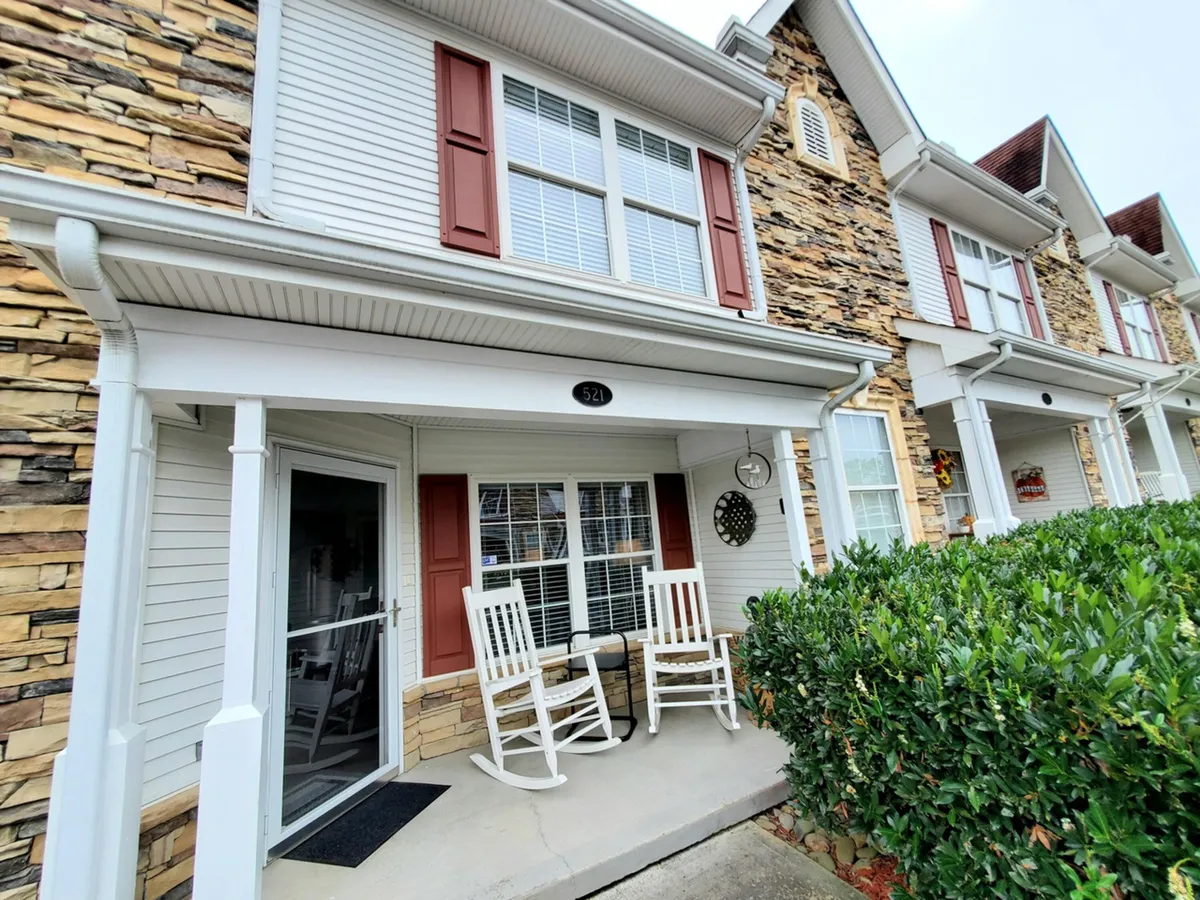 The inviting front porch of a rustic building, featuring rocking chairs, a rocky facade, and a window with shutters. The space is ideal for enjoying morning coffee or quiet, intimate moments while soaking in the peaceful resort environment.