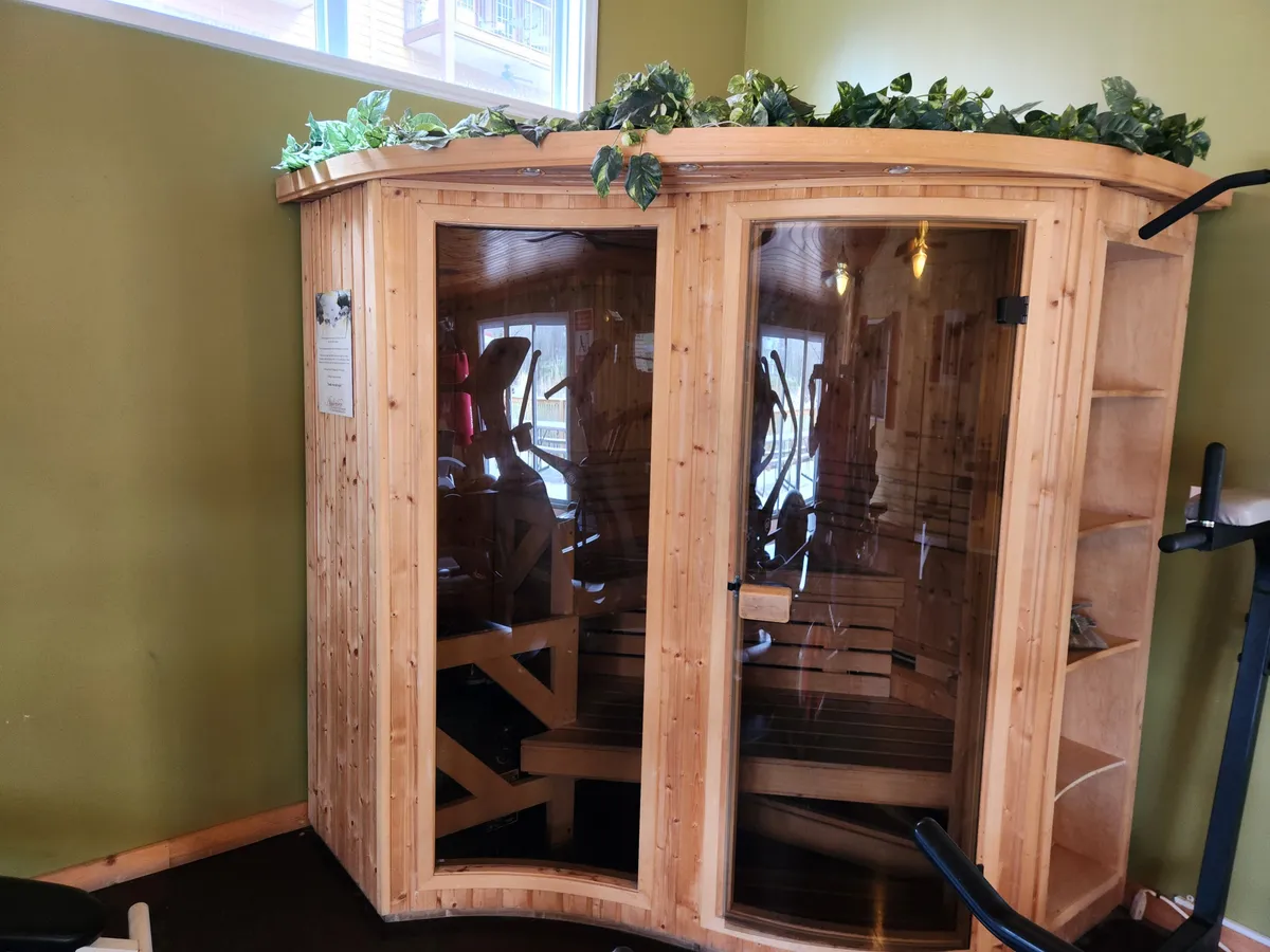 A serene wellness area featuring a wooden sauna with lush greenery atop, situated next to exercise equipment. The calming ambiance is ideal for relaxation and recovery after a workout, emphasizing the resort’s holistic wellness offerings.