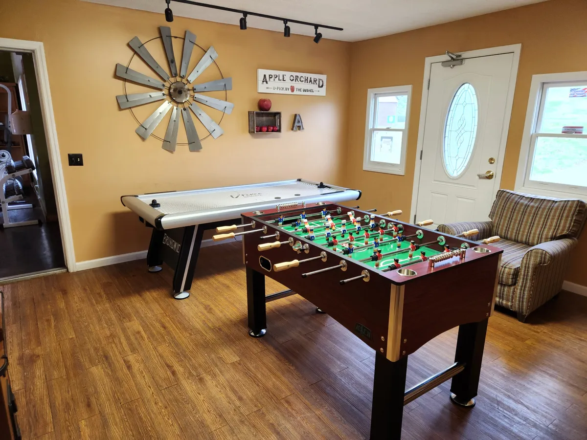 An inviting interior showing a foosball table, air hockey table, stylish wall art, and a comfortable chair. The room is designed to foster relaxation and playful gatherings, perfect for both family tournaments and casual gaming sessions.